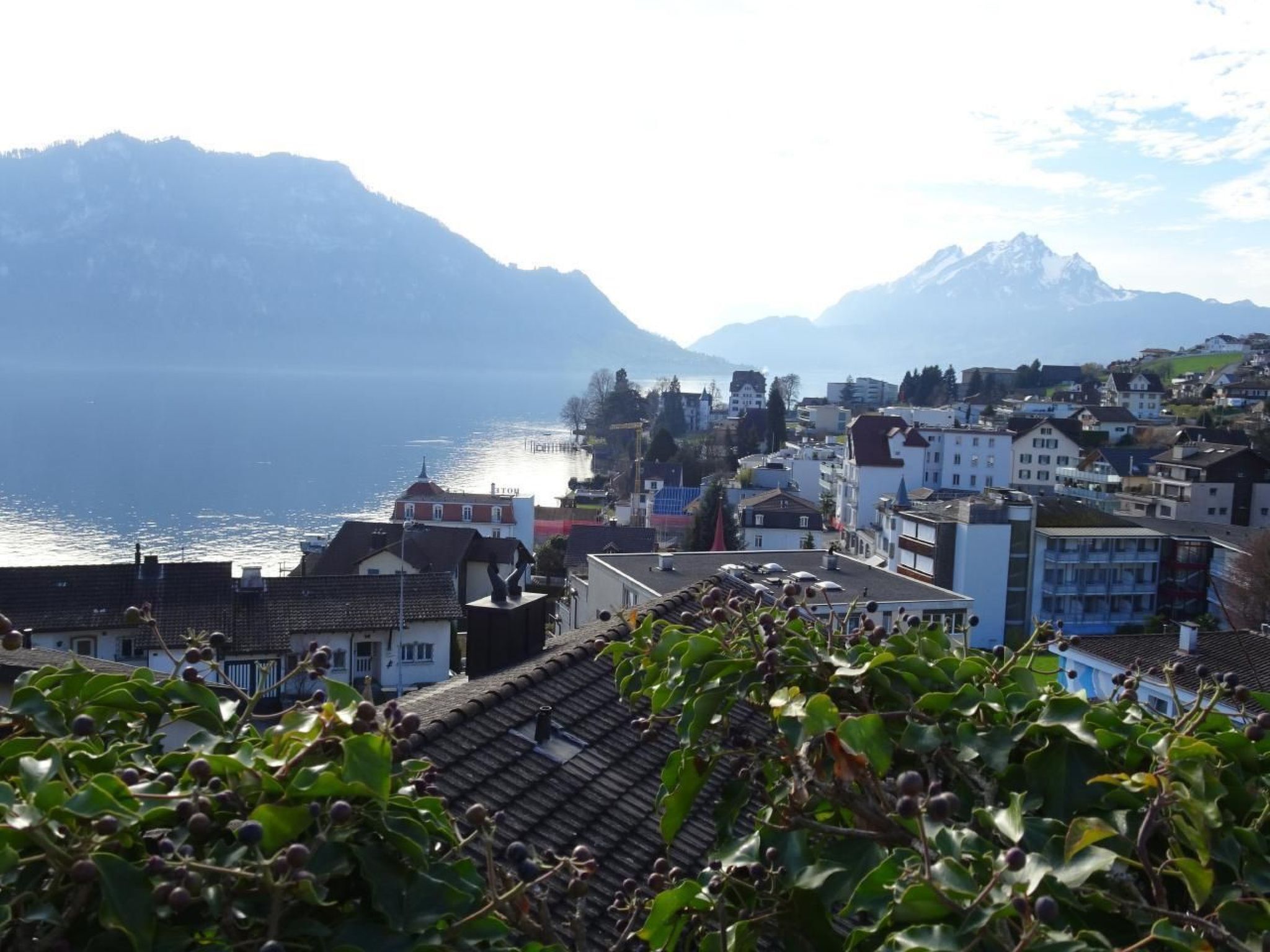 A coastal town with buildings along the waterfront, a mountain range in the background, and a view of the sea.