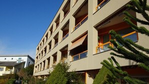 A multi-story building with balconies, surrounded by greenery and other residential buildings. - Wohnung mit herrlichem Blick auf den Pilatus by Interhome (Weggis)