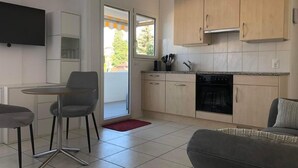 A compact kitchen with a dining area, a sofa, and a TV mounted on the wall. - Studio "Rubi" Weggis by Interhome (Weggis)