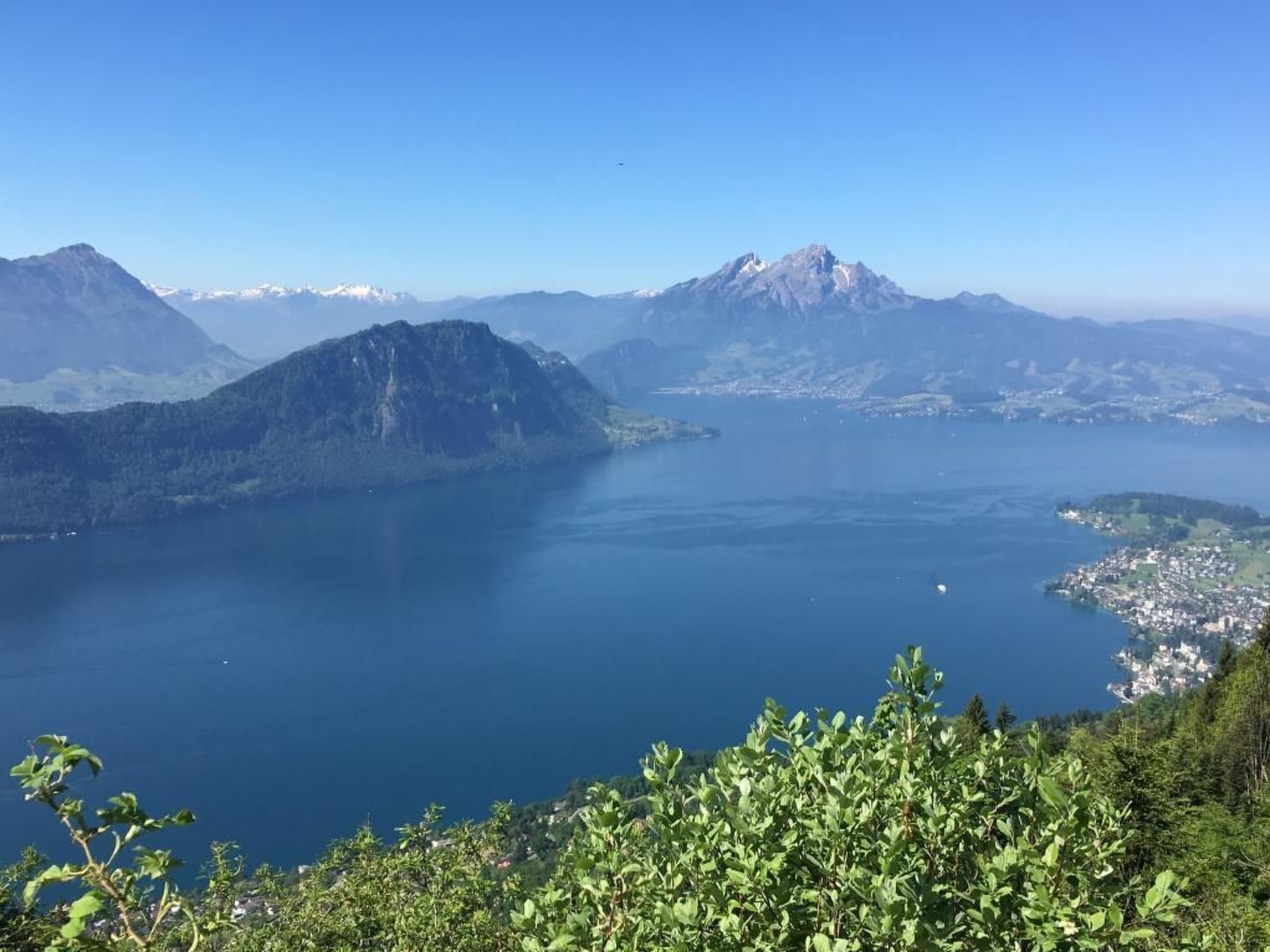 Vista panorámica de un paisaje montañoso con un lago y un pueblo pequeño.
