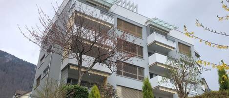 Un immeuble à plusieurs étages doté d’une architecture moderne, avec des balcons et une façade en verre.