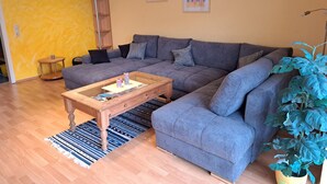 A living room with a sectional sofa, a coffee table, a plant, and two framed pictures on the wall. - Vacation home Sina by Interhome (Bannesdorf)