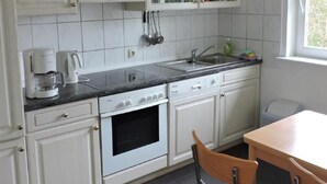 A kitchen with white cabinets, a stove, a sink, and a window. - Vacation home Sina by Interhome (Bannesdorf)