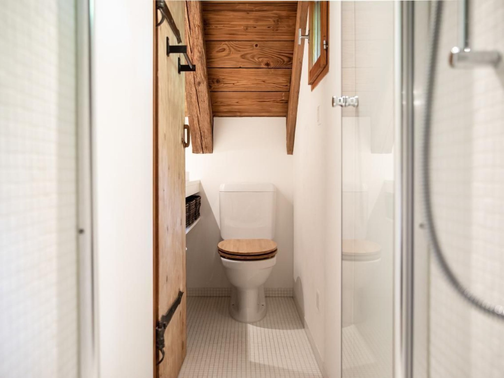 A compact bathroom with a wooden vanity, a white toilet, and a glass shower enclosure.
