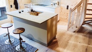A modern kitchen with a central island, wooden walls, and a small dining area with stools. - SPYCHER WEGGIS by Interhome (Weggis)