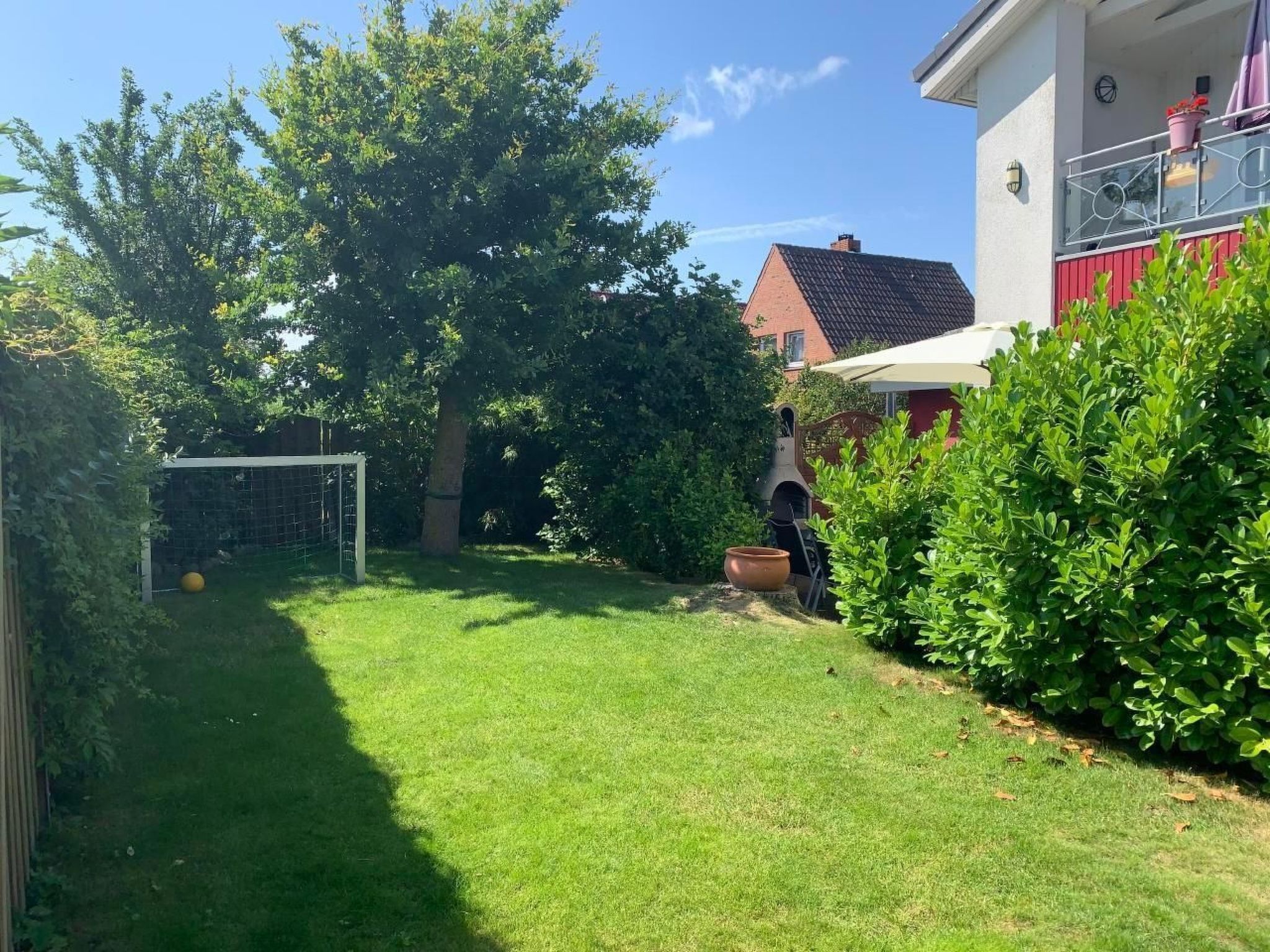 A well-maintained backyard with a lawn, a soccer goal, and a barbecue grill.