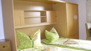 Un dormitorio con dos camas, un armario de madera y una silla.
