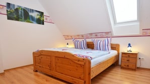 Une chambre à coucher avec un lit en bois, une table de chevet, une lampe et une fenêtre.