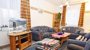Un salon confortable avec un téléviseur, deux canapés, une table basse et un tapis à motifs.