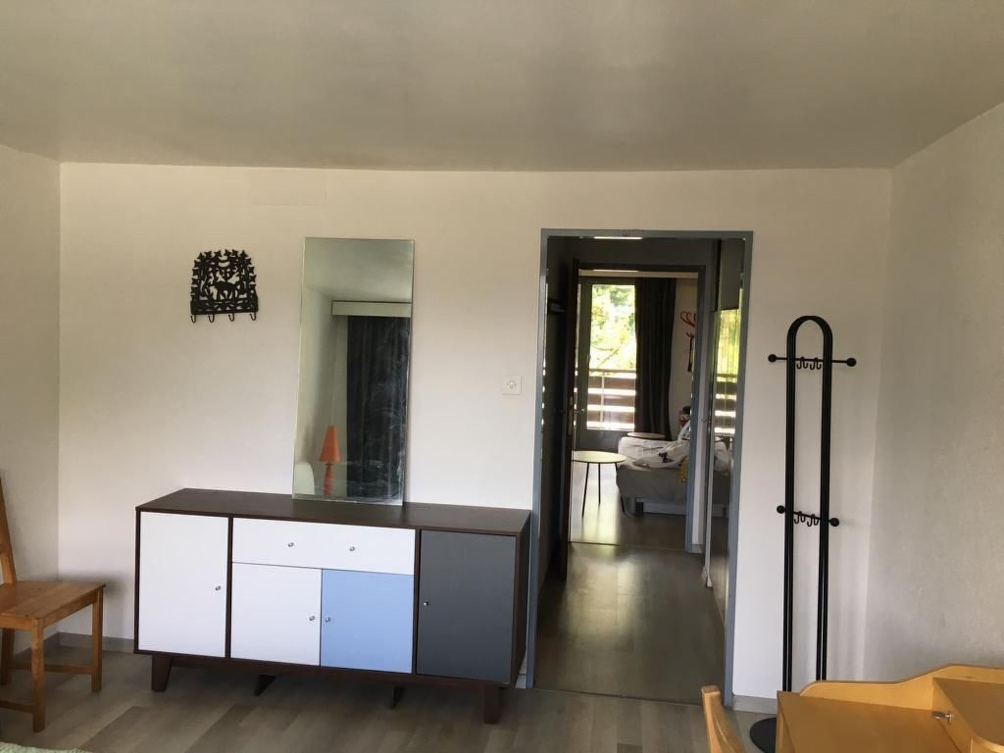 Una habitación con un armario de madera, un espejo y una puerta que da a otra estancia.