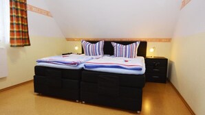 Ein Doppelbett mit gestreifter Bettwäsche, ein schwarzer Kopfteil und zwei Nachttische mit Lampen.
