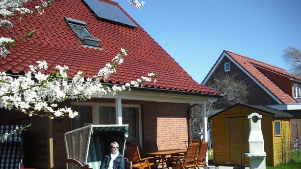 Ein Haus mit rotem Ziegeldach, einer Ziegelaußenwand und einer Veranda mit Gartenmöbeln.