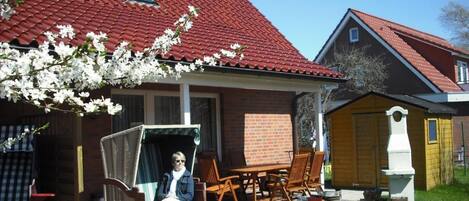 A house with a red tiled roof, a brick exterior, and a porch with outdoor furniture.
