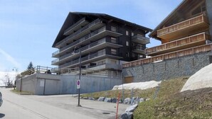 Ein mehrstöckiges Gebäude mit Balkonen, einem Parkplatz und einer Steinmauer.