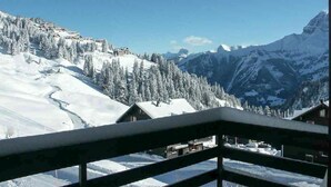 Eine verschneite Berglandschaft mit einer Holzhütte und blauem Himmel.