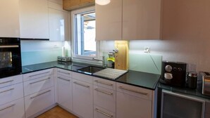 Eine moderne Küche mit weißen Schränken, einer schwarzen Arbeitsplatte und einer Holzbalkendecke.