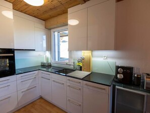 A modern kitchen with white cabinets, a black countertop, and a wooden ceiling. - 3 Zi FeWo App 23. Le Miroi an Skipiste by Interhome (Les Crosets)