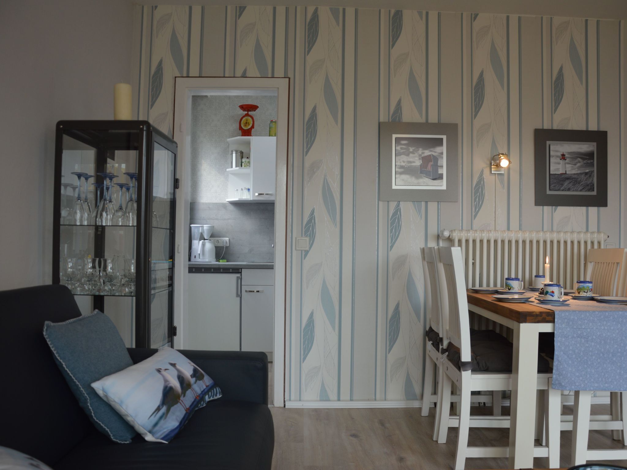 Un espace de vie compact comprenant un coin cuisine, un coin repas avec une table et des chaises, et un canapé avec un coussin.