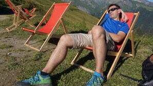 A person sitting on a red lounge chair in a grassy outdoor area with a mountainous backdrop. - Osttirol by Interhome (Kals am Großglockner)
