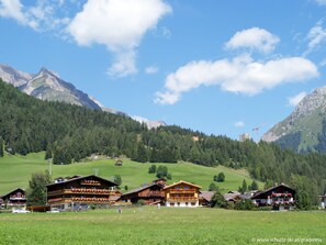 A mountain lodge with multiple floors, outdoor seating, and a view of the surrounding mountains. - Osttirol by Interhome (Kals am Großglockner)