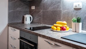 Una cocina moderna con horno empotrado, hervidor y frutero sobre la encimera.