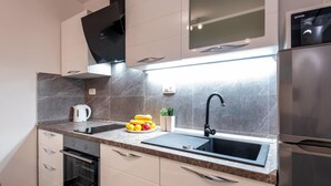 Una cocina moderna con un lavaplatos de acero inoxidable, horno empotrado y campana extractora negra.