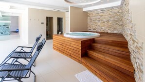 Ein moderner Wellnessbereich mit einer Holzbank, einem Whirlpool und einer Steinwand.