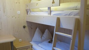 Ein Schlafzimmer mit Etagenbett, Holzleiter, Nachttisch und Wandsteckdose.