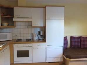 A compact kitchen with white appliances, a microwave, a coffee maker, and a stove. - Appartement Elena by Interhome (Umhausen)