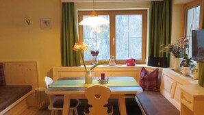 Ein gemütlicher Essbereich mit Holztisch und -stühlen, einer Bank und einem Fenster mit Vorhängen.