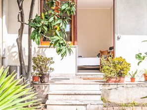 A stone staircase leading to a room with a bed and a chair, surrounded by potted plants. - Die Orange und der Goldfisch by Interhome (Calatabiano)