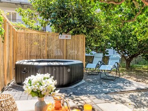 A hot tub, lounge chairs, and a wicker basket with flowers and a pitcher of orange juice. - Die Orange und der Goldfisch by Interhome (Calatabiano)