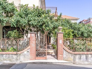 A gated entrance with a wrought iron gate, brick pillars, and a clear pathway leading to a building with a tiled roof. - Die Orange und der Goldfisch by Interhome (Calatabiano)