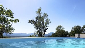 A swimming pool with clear blue water, surrounded by trees and a mountain view. - La Finca OliveTree by Interhome (Katuni)