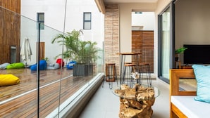 Ein moderner Wohnraum mit Glastrennwand, Holzdeck und Glastisch.