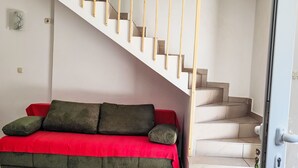A room with a red sofa, a staircase, and a door. - Gemütliche Ferienwohnung Emil by Interhome (Dragišina)
