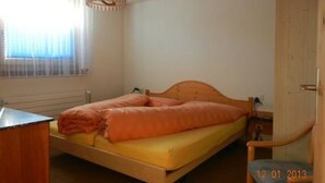 Ein Einzelbett mit Holz Kopfteil in einem Zimmer mit Fenster und Tür.