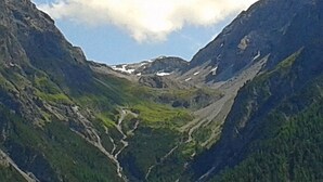 Eine gebirgige Landschaft mit einem Tal und einer Serpentinenstraße.