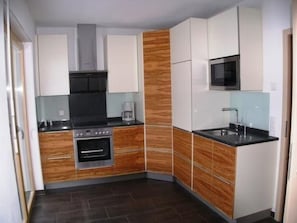 A compact kitchen with white cabinets, a built-in oven, a microwave, and a coffee maker.
