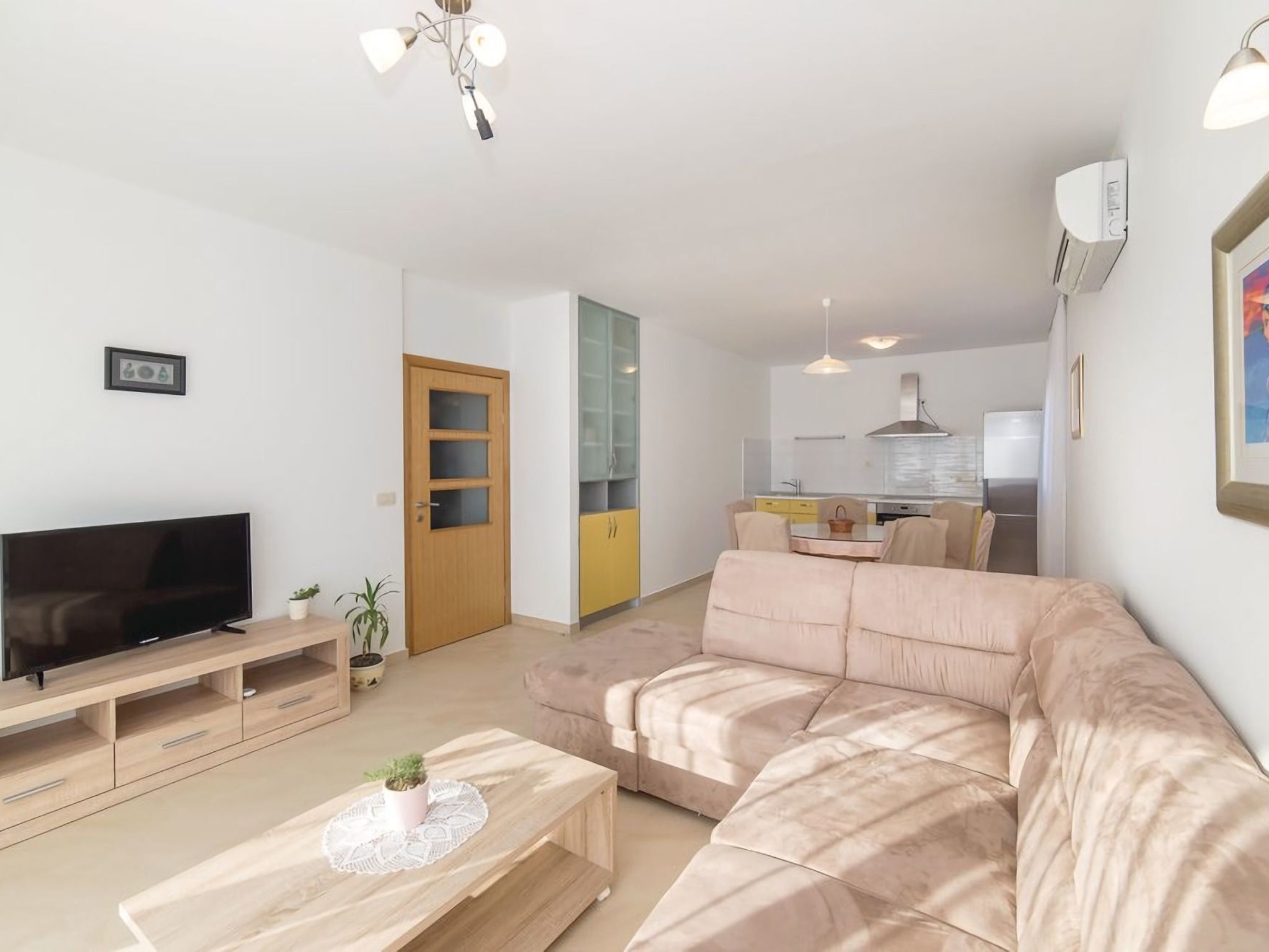 A modern living room with a flat-screen TV, a wooden coffee table, and a beige sofa.