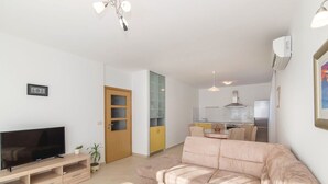 Een moderne woonkamer met een flatscreen televisie, een houten salontafel en een beige bank.