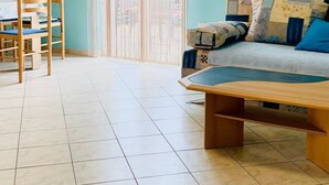 Una stanza con soffitto spiovente, un letto con testiera in legno, un tavolo, una sedia, un quadro e un condizionatore d'aria.
