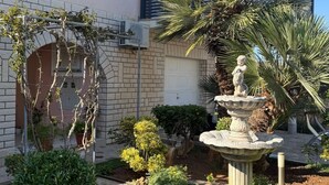 Un giardino con una fontana, una palma e diverse piante.