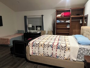 Une chambre à coucher comprenant un lit, un bureau, une chaise, une armoire et un téléviseur.