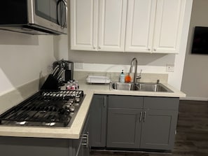 A kitchen with a gas stove, a coffee maker, a microwave, and a sink with a faucet. - Cozy 1-bedroom studio in charming Los Angeles with AC (Los Angeles)