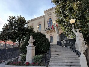 Ein prächtiges Gebäude mit einer Treppe, Statuen und einem Büstenporträt.