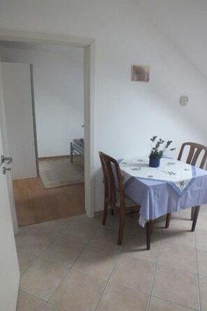 Een eethoek met een tafel gedekt voor twee personen, houten stoelen en een kleine potplant op de tafel.