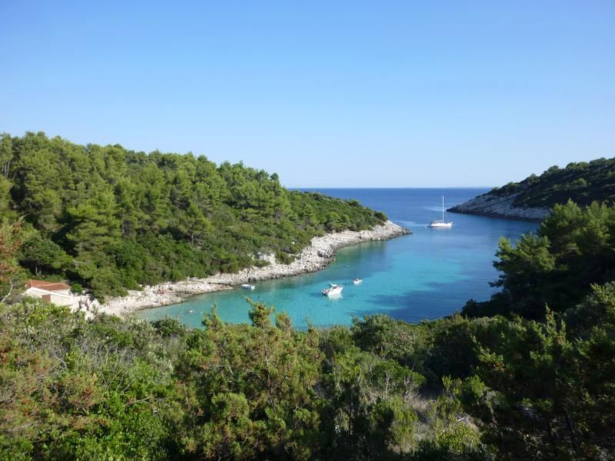 Un paysage côtier offrant une vue dégagée sur la mer, avec un petit bateau et un bâtiment situé sur la plage.