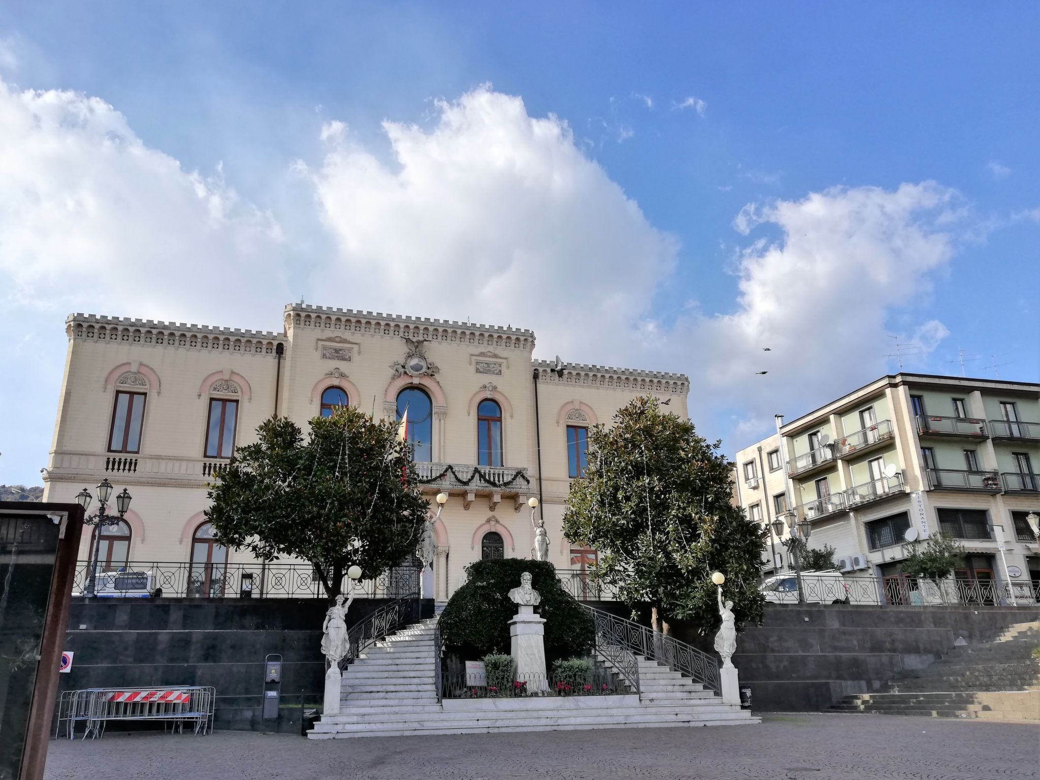 Un edificio histórico con una entrada imponente, una escalera que conduce a las puertas principales y una estatua en la base.