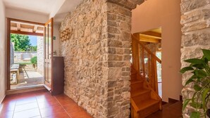 Un pasillo con paredes de piedra y una escalera de madera que sube a un nivel superior.